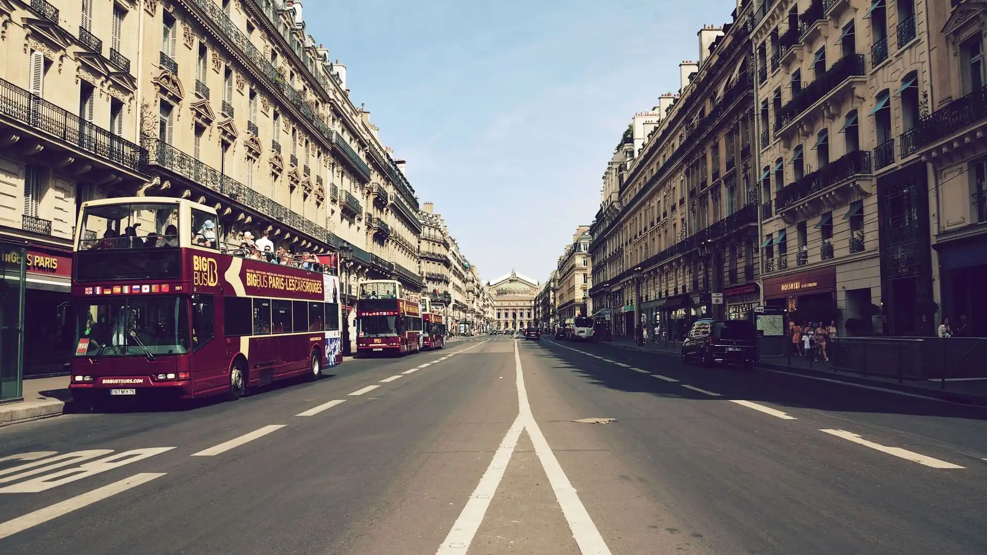 Double-decker sightseeing buses on a Haussmann street in central Paris