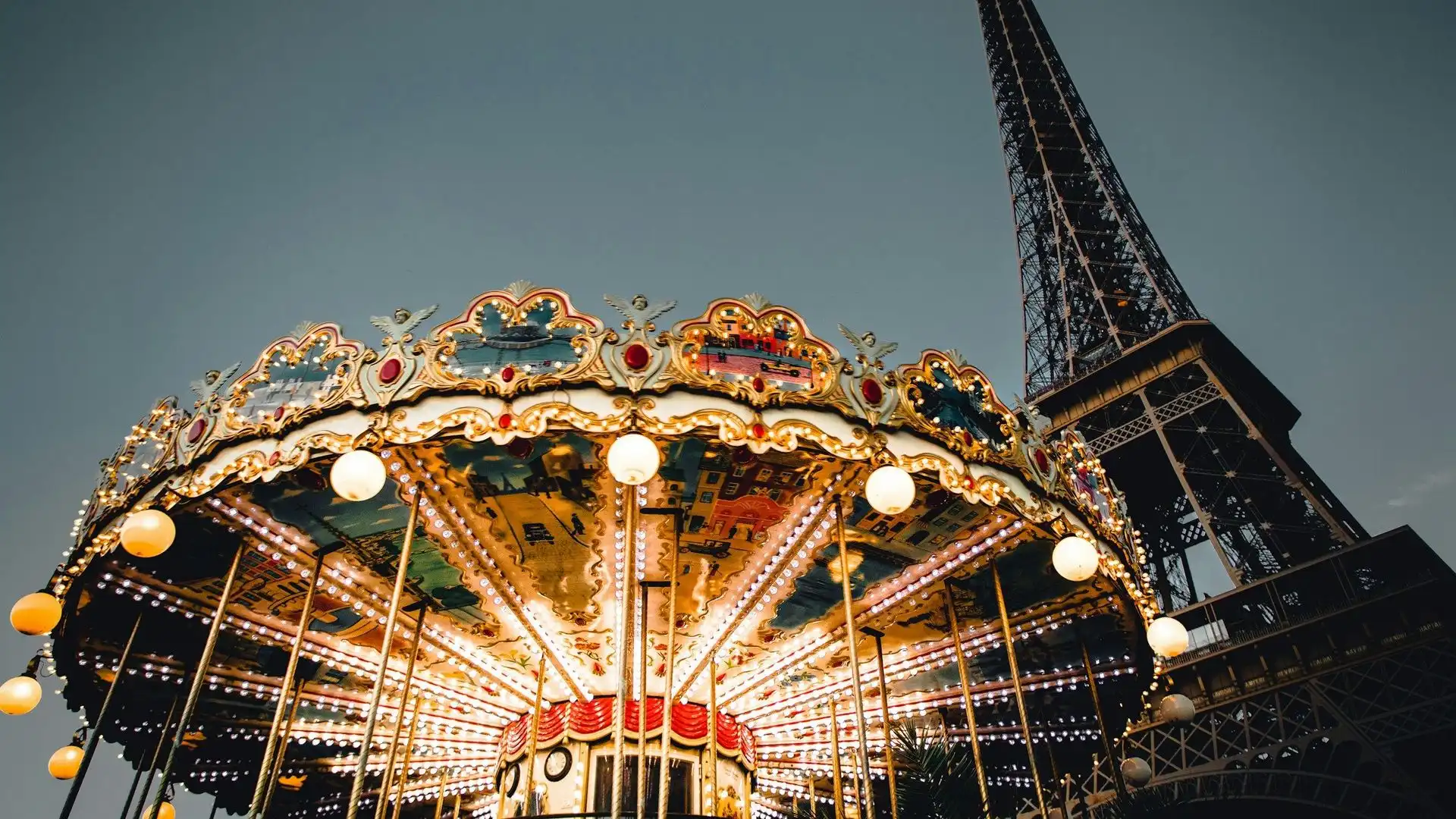Lit carousel at the foot of the Eiffel Tower in the evening